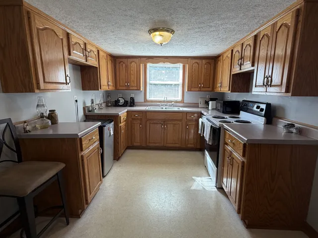 a kitchen with stainless steel appliances granite countertop a stove top oven a sink dishwasher and wooden cabinets