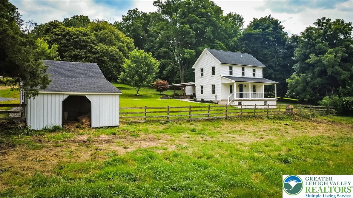 72 Allegheny Road Mount Bethel, PA 18343 - Photo 56 of 72 A charming farmhouse and barn set against a backdrop of lush greenery, offering serene rural living.