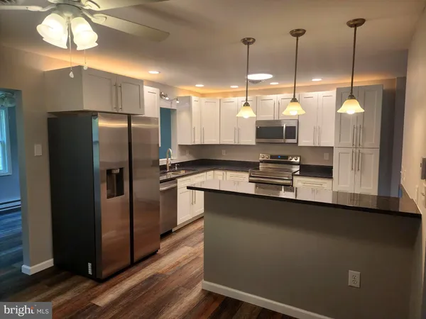 a kitchen with stainless steel appliances a refrigerator a sink a stove and a wooden floors