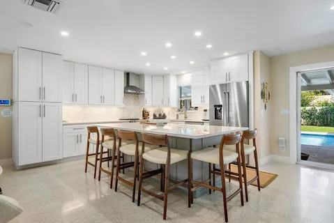 a kitchen with stainless steel appliances kitchen island granite countertop a dining table chairs and white refrigerator