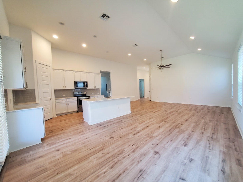 648 Peace Pipe Way Georgetown, TX 78628 - Photo 2 of 12 a large kitchen with kitchen island a stove a sink dishwasher and a refrigerator with wooden floor