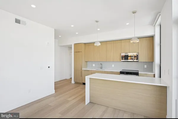 a view of a kitchen with kitchen island a sink stainless steel appliances and cabinets