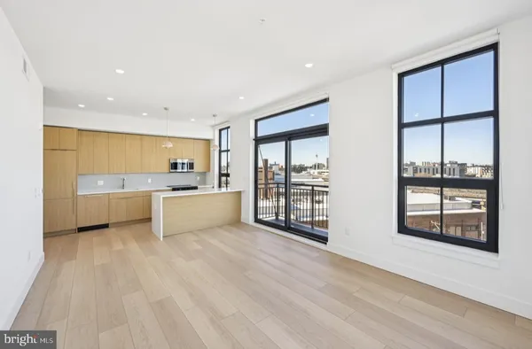 a large white kitchen with stainless steel appliances granite countertop a large window and a sink