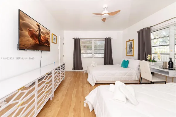 a spacious bedroom with a bed a flat screen tv and windows