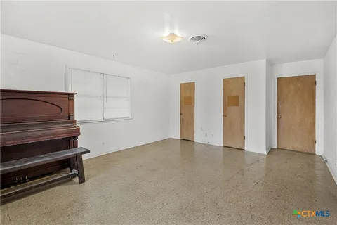 a view of an empty room with wooden floor and windows