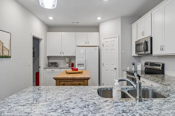 a kitchen with stainless steel appliances granite countertop a sink stove and refrigerator