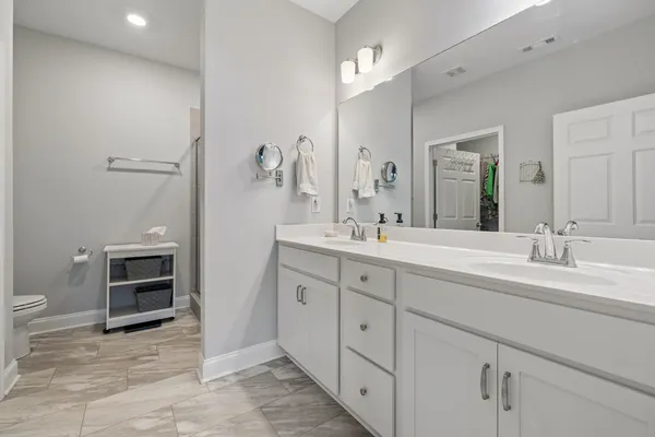 a spacious bathroom with a double vanity sink a mirror and a toilet