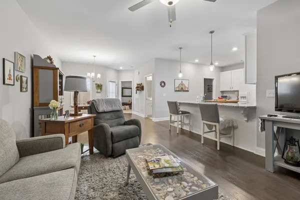 a living room with furniture kitchen view and a wooden floor