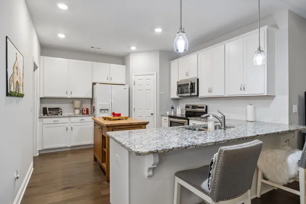 a kitchen with kitchen island granite countertop a sink cabinets and stainless steel appliances