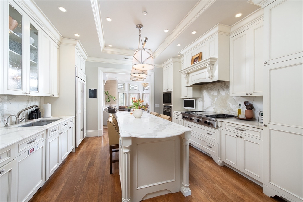 304 Commonwealth Avenue, Unit PH Boston, MA 02115 - Photo 10 of 42 a large kitchen with stainless steel appliances kitchen island granite countertop a stove a sink a refrigerator and white cabinets with wooden floor