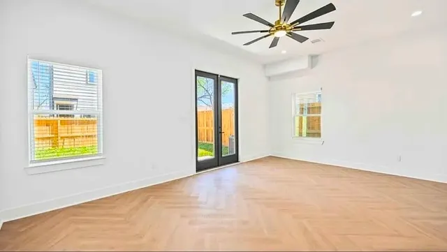 an empty room with windows and fan
