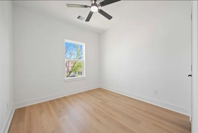 an empty room with a window and a ceiling fan