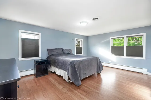 a spacious bedroom with a bed and wooden floor