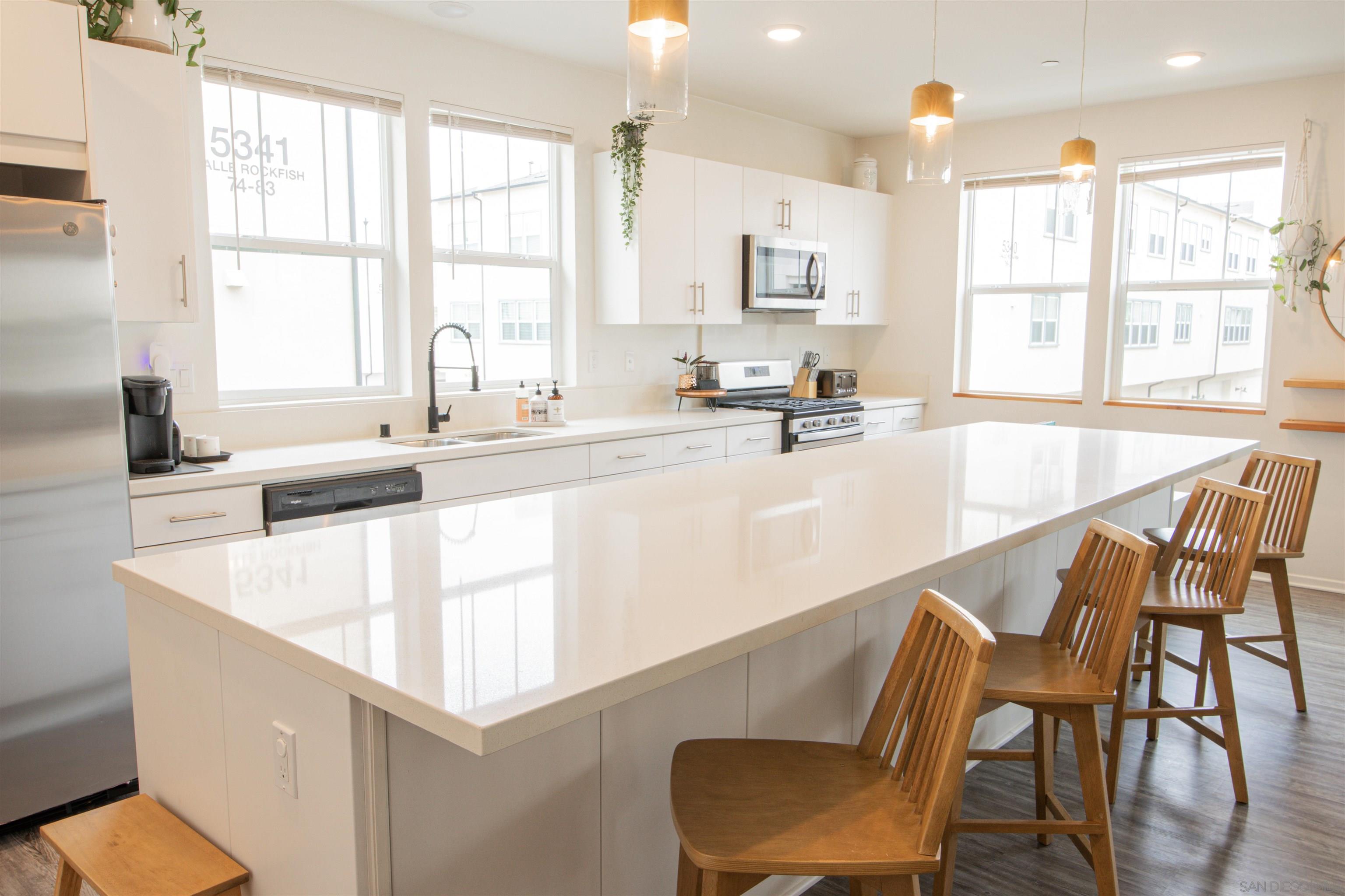 a large white kitchen with granite countertop a stove a sink a dining table and chairs
