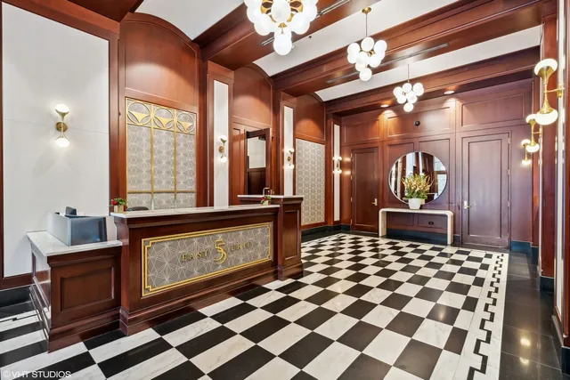 a living room with a black white checkered floor with couches chair and a coffee table