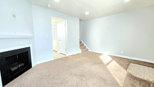 8732 Fairoaks Circle Sandy, UT 84070 - Photo 10 of 18 Unfurnished living room with light colored carpet, a fireplace, and recessed lighting
