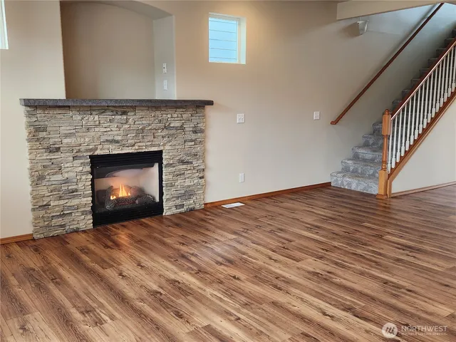a view of an empty room with wooden floor fireplace and a window