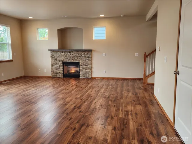 an empty room with wooden floor a fireplace and windows