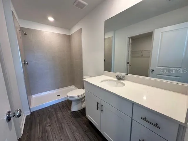 a bathroom with a double vanity sink toilet mirror and shower