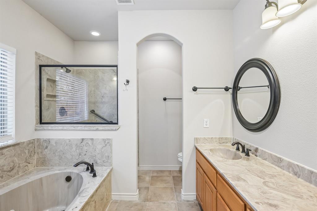 2617 Kirby Road Rowlett, TX 75088 - Photo 13 of 35 Soaking tub with stone-look surround, walk-in shower with glass enclosure, single vanity with stone-look countertop, integrated sink, and bronze-finish fixtures