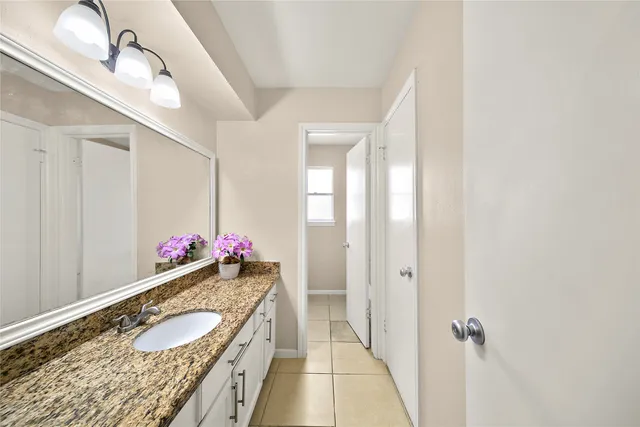 a bathroom with a granite countertop sink a mirror and a shower