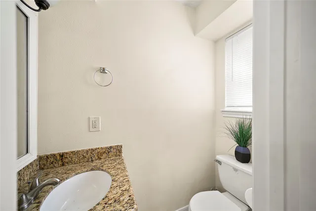 a bathroom with a granite countertop toilet and a sink