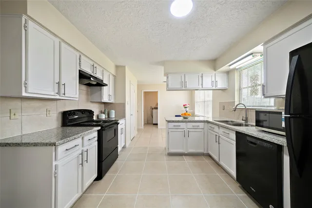 a kitchen with stainless steel appliances granite countertop a sink stove refrigerator and white cabinets