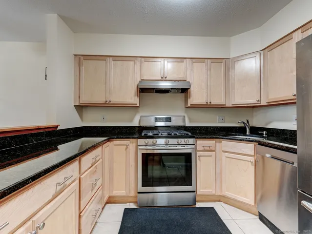 a kitchen with stainless steel appliances granite countertop a stove and white cabinets