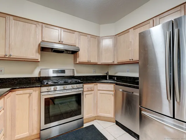 a kitchen with stainless steel appliances granite countertop a stove a refrigerator and a cabinets