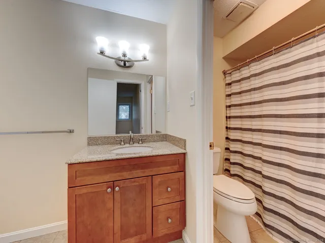 a bathroom with a granite countertop sink toilet and mirror