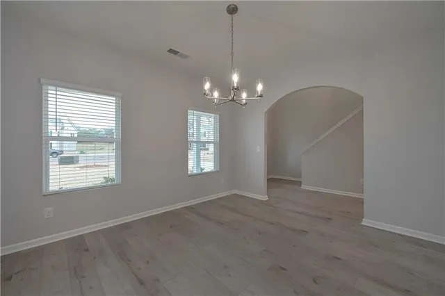 an empty room with chandelier fan and windows