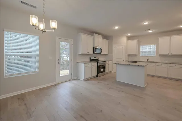 a large kitchen with cabinets wooden floor and stainless steel appliances