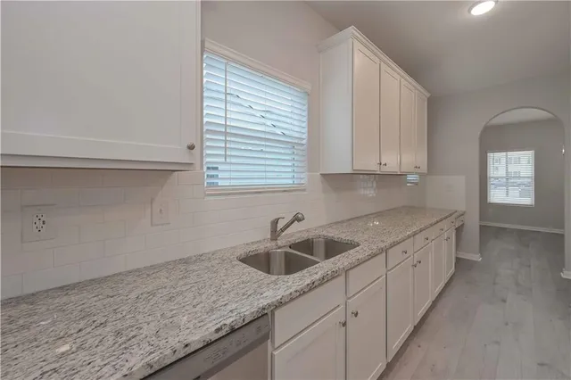 a kitchen with granite countertop white cabinets and sink