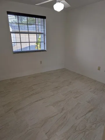 an empty room with wooden floor chandelier and windows