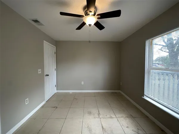 an empty room with windows and fan