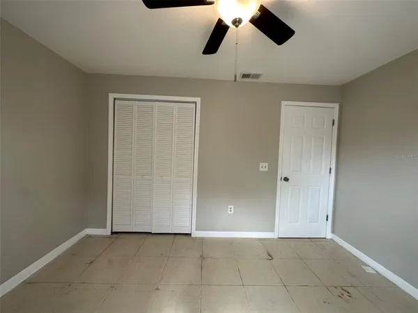 en empty room with closet and chandelier fan