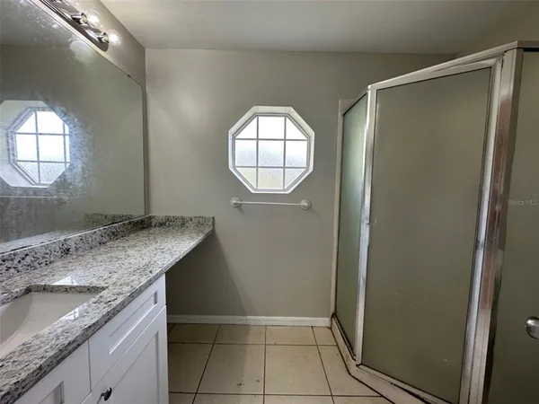 a bathroom with a granite countertop sink a mirror and a shower