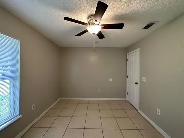 an empty room with ceiling fan and window