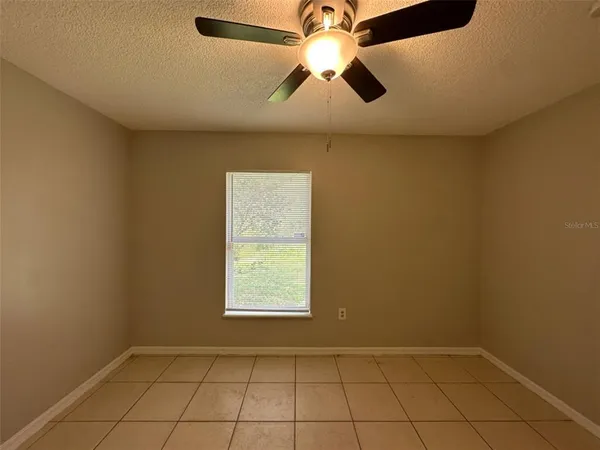 an empty room with windows and fan