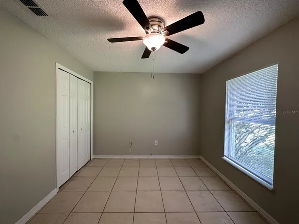 an empty room with windows and fan