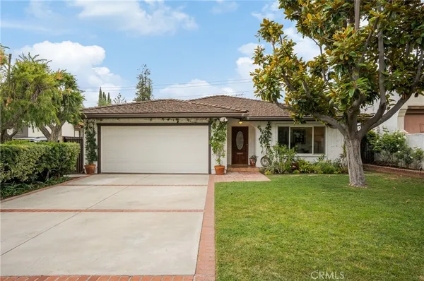 a front view of a house with a garden and trees