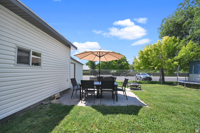 331 West 300 North Logan, UT 84321 - Photo 23 of 28 Concrete patio area featuring a table and chairs, bordered by a manicured lawn
