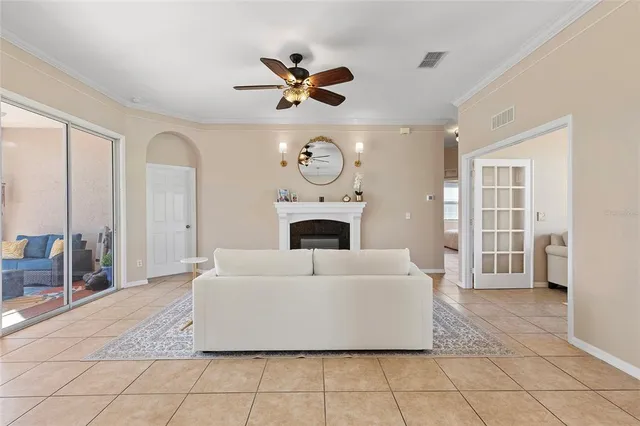 a living room with a fireplace furniture a ceiling fan and a rug