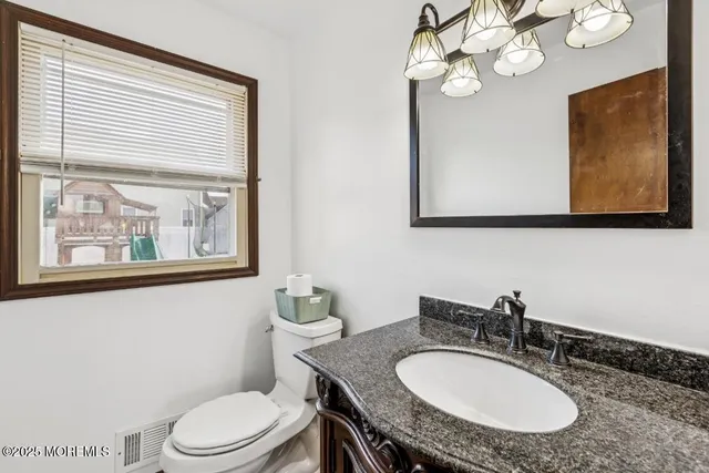 a bathroom with a granite countertop toilet a sink and mirror