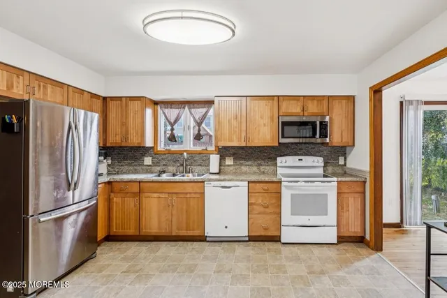 a kitchen with stainless steel appliances granite countertop a refrigerator stove top oven and sink
