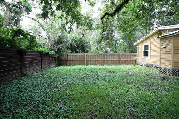 a view of a backyard with a large tree and wooden fence