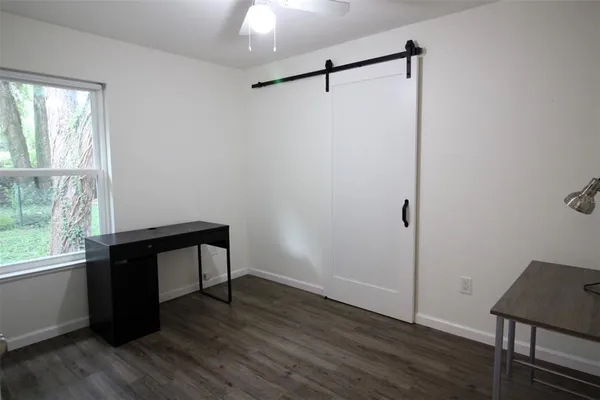 an empty room with wooden floor a ceiling fan and windows