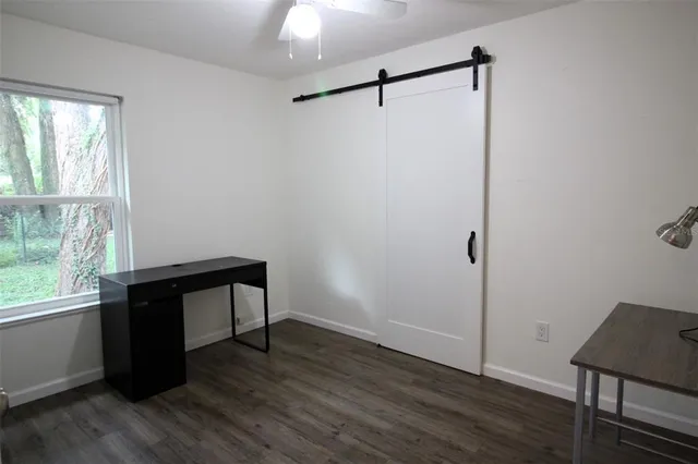 an empty room with wooden floor a ceiling fan and windows