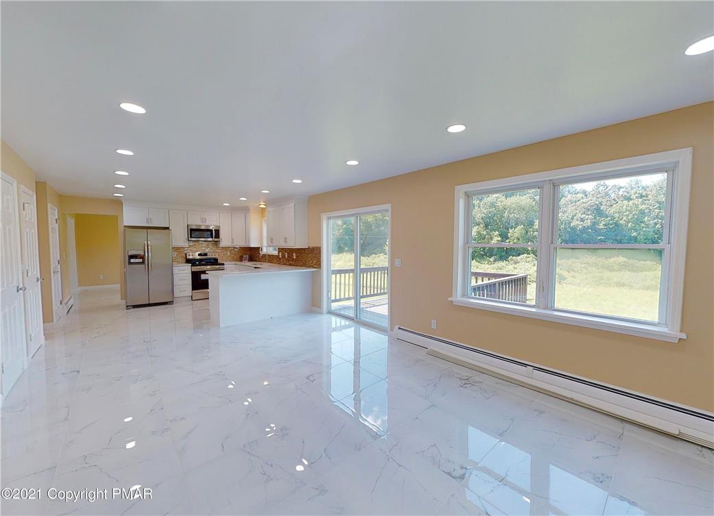 1110 Misty Ridge East Stroudsburg, PA 18302 - Photo 16 of 43 A well-lit kitchen and living area, featuring sleek white flooring and natural outdoor views.
