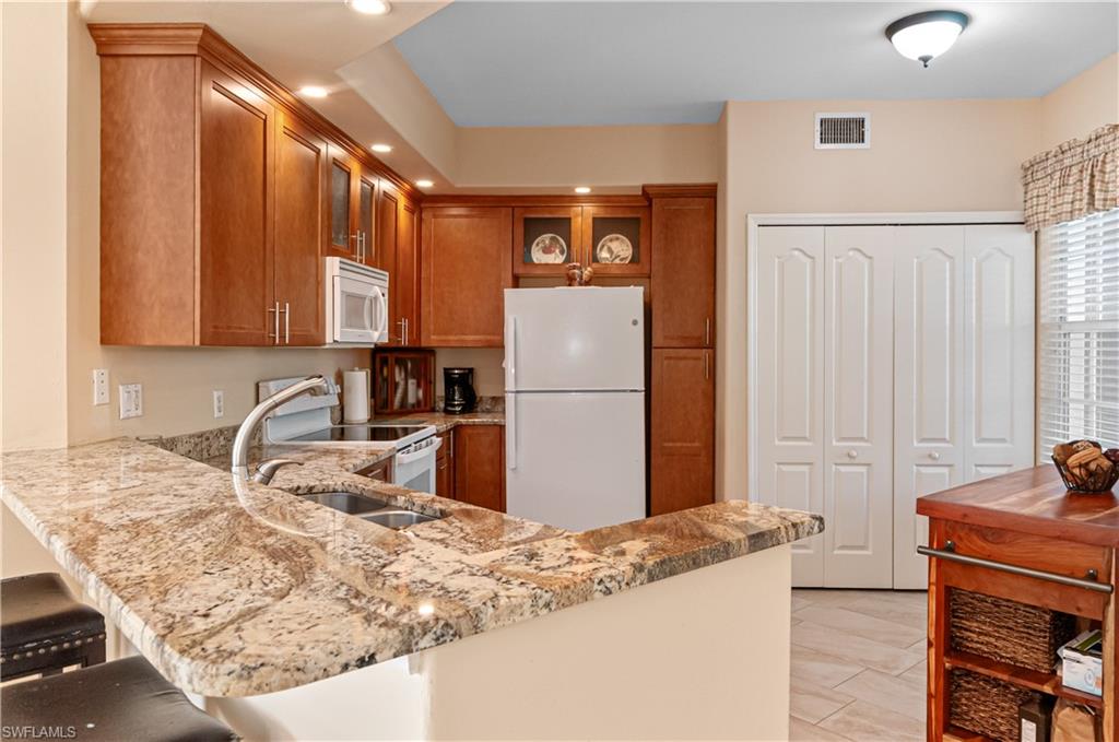 9030 Spring Run Boulevard, Unit 507 Estero, FL 34135 - Photo 4 of 21 a kitchen with stainless steel appliances granite countertop a refrigerator and a sink